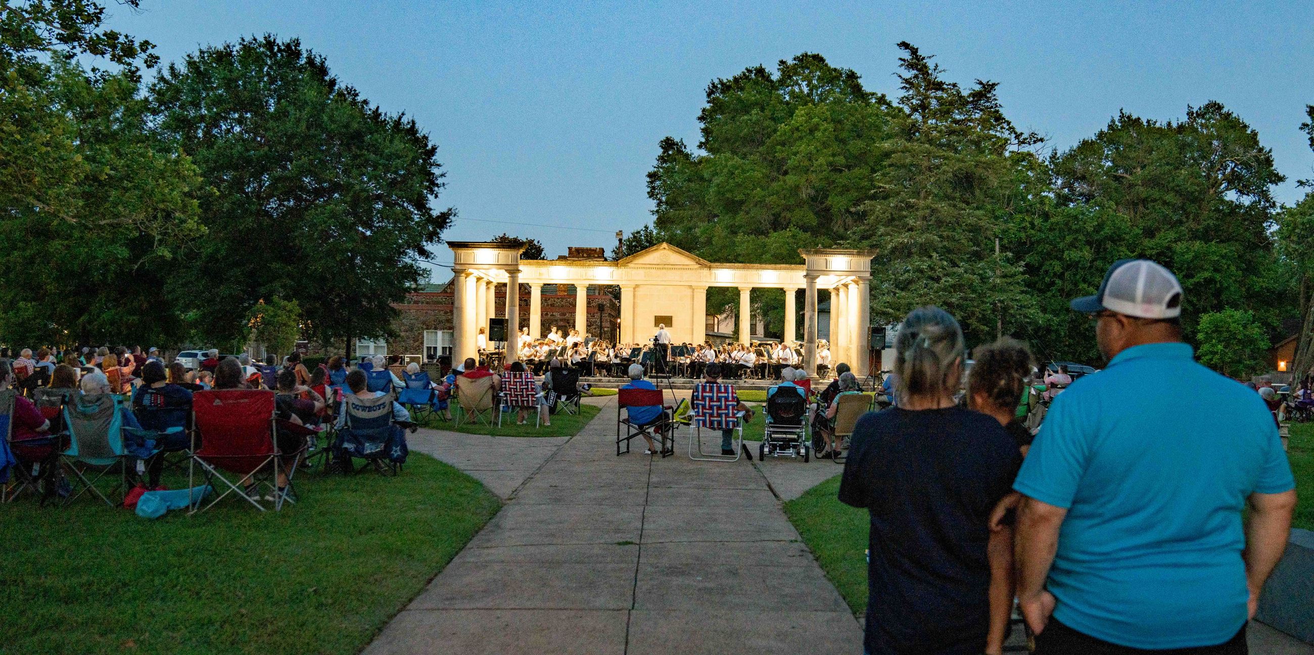People along the main sidewalk of Bywaters Park watch Paris Municipal Band