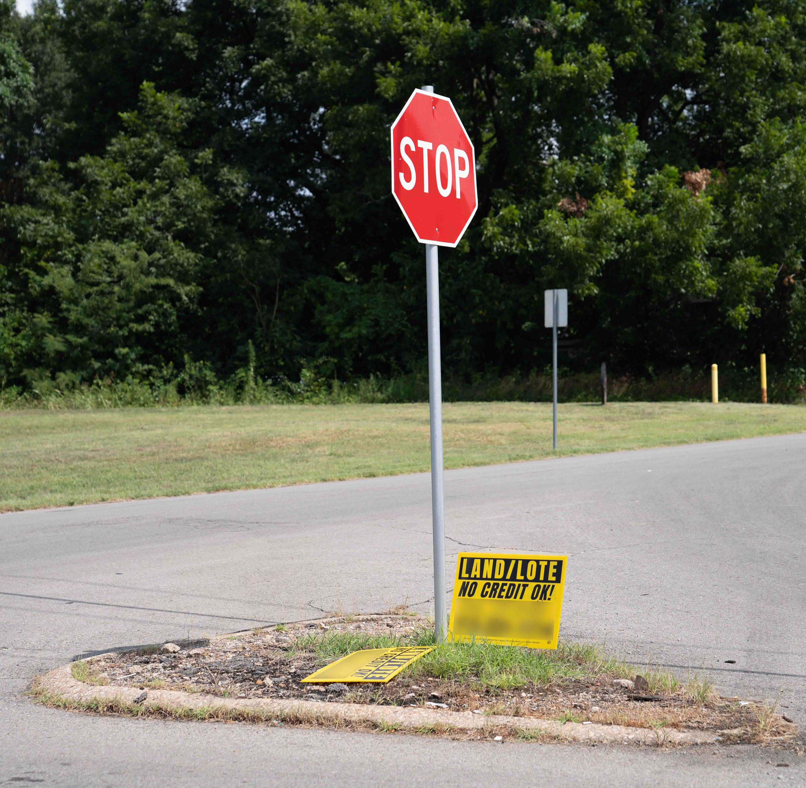 picture of stop sign island with illegally placed for sale sign in the right of way